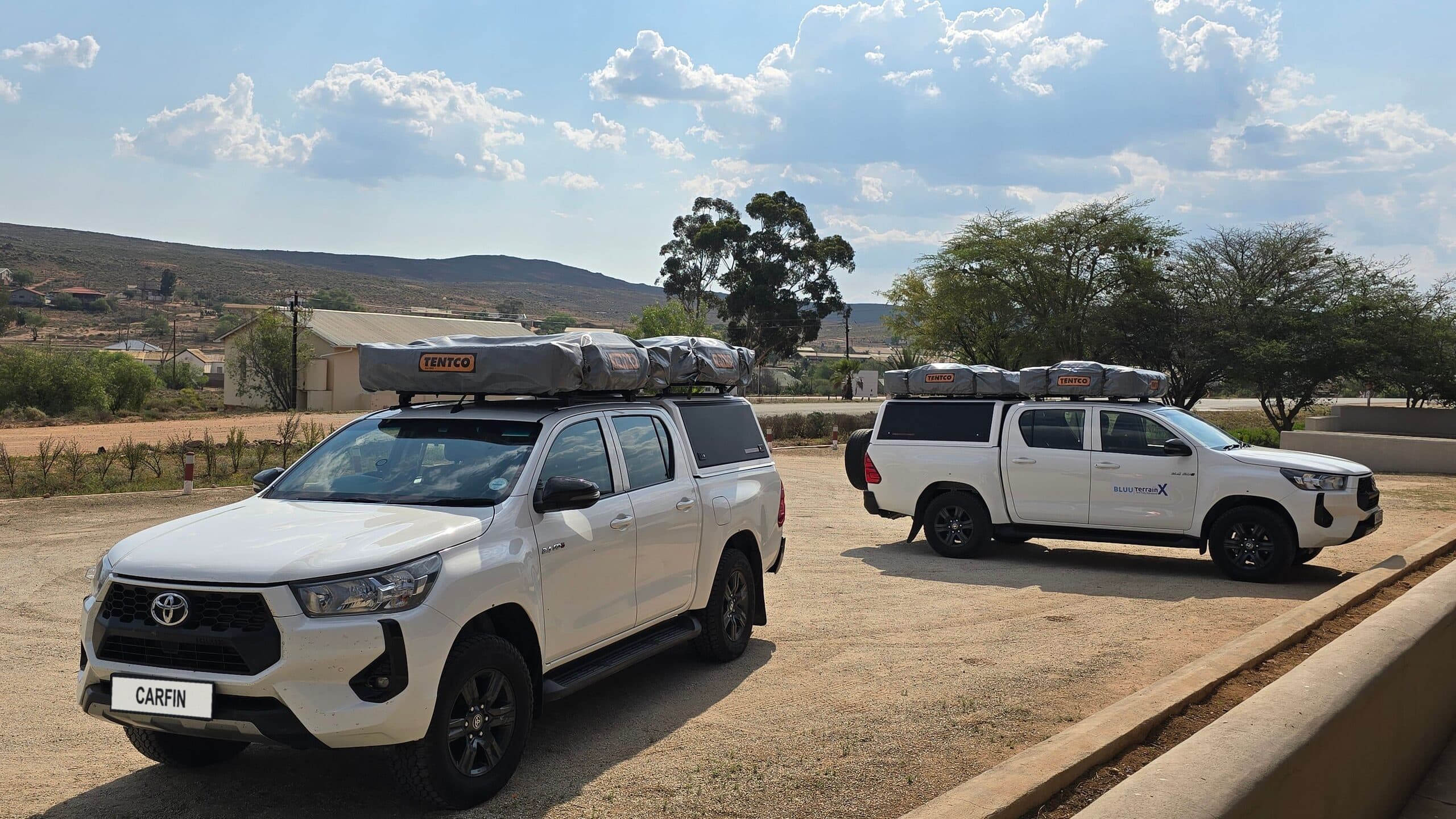 Two white Toyota Hilux double cabs from a company fleet